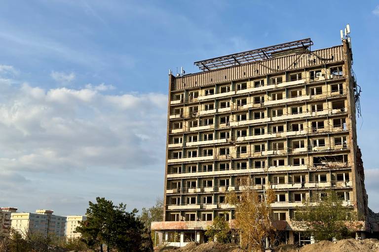 Antigo hotel da Azovstal, destruído, ao lado de prédios novos em Mariupol