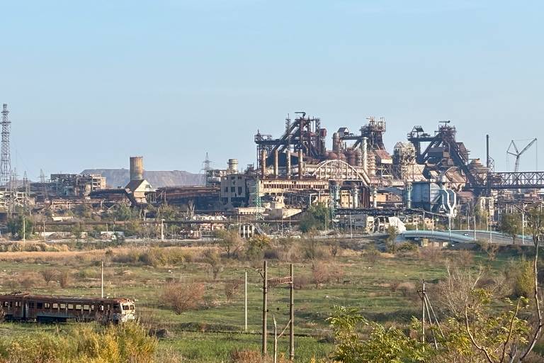 Ruínas da fábrica Azovstal, com o trem destruído em 2022 com refugiados à frente