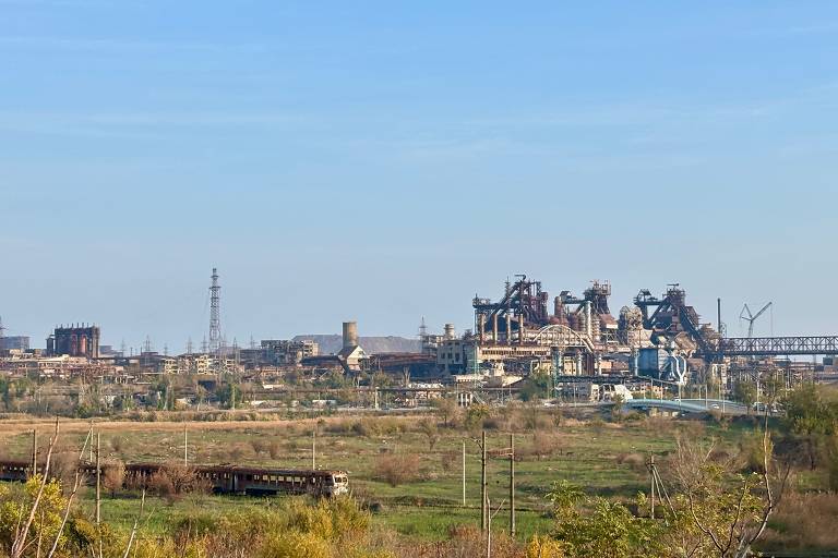 Ruínas da fábrica de aço Azovstal com trem de refugiados destruído no início da guerra à frente