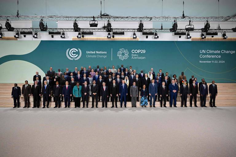 A imagem mostra um grupo de pessoas posando em um evento da Conferência das Nações Unidas sobre Mudanças Climáticas (COP). Há uma variedade de líderes e representantes de diferentes países, todos alinhados em várias fileiras, com um fundo que exibe os logotipos da ONU e da COP. O ambiente é formal e bem iluminado.