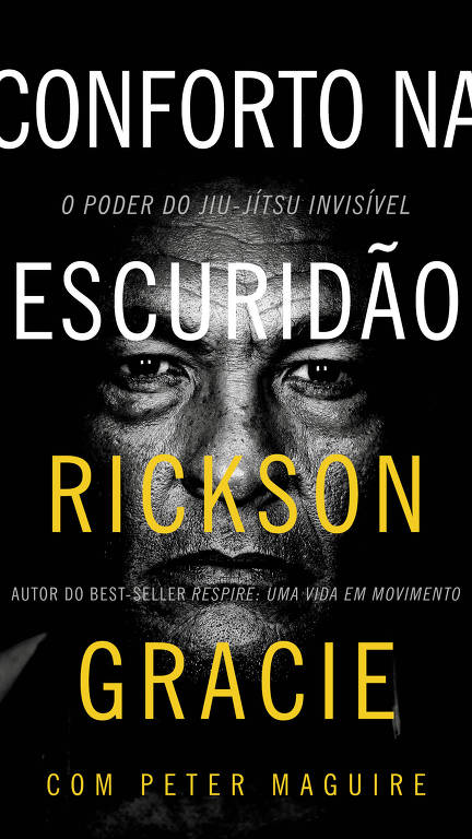 A imagem apresenta a capa do livro 'Conforto na Escuridão', com um fundo preto. O título está em letras grandes e brancas, com a palavra 'ESCURIDÃO' em destaque amarelo. Abaixo, está o nome 'RICKSON GRACIE' em amarelo, seguido pela frase 'AUTOR DO BEST-SELLER RESPIRA: UMA VIDA EM MOVIMENTO' em letras brancas menores. O autor é acompanhado por 'COM PETER MAGUIRE'. A imagem inclui um retrato de um homem com expressão séria, destacando detalhes de seu rosto.