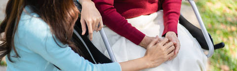 Family relationship Asian senior woman in wheelchair with happy daughter holding caregiver for a hand while spending time together. Credit AdobeStock