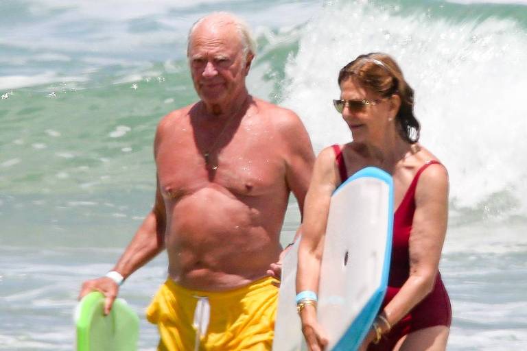 Em foto colorida, casal se diverte na praia