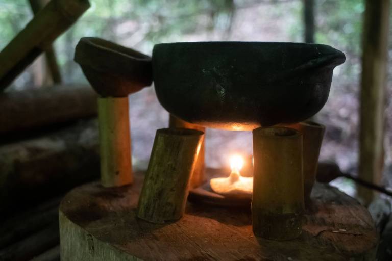 Panela sobre pequena chama sustentada sobre tocos de bambu