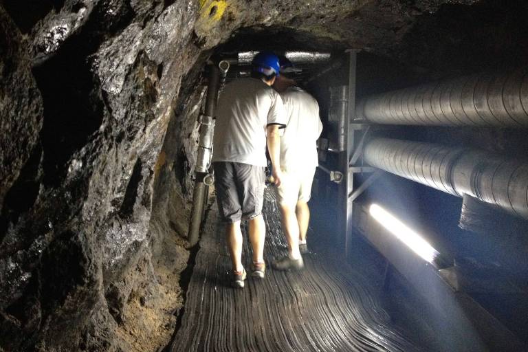 Turistas caminham abaixados dentro do Terceiro Túnel， um dos atrativos da zona desmilitarizada na fronteira das Coreias do Norte e do Sul