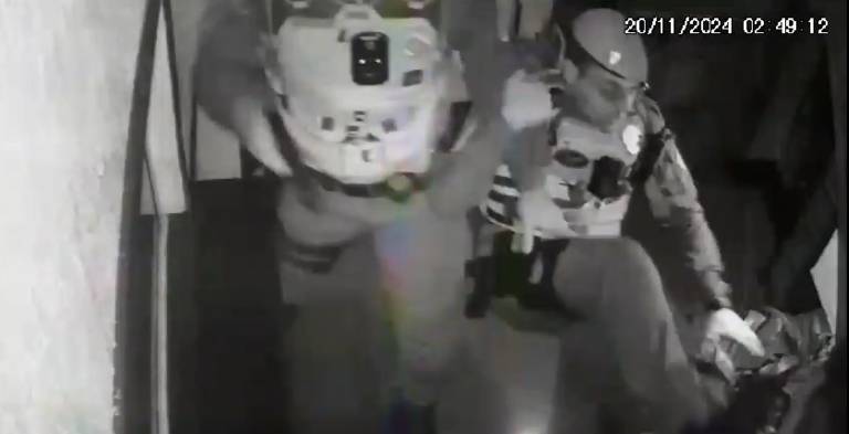 Um dos militares dá um chute nele e é agarrado pela perna. O policial se desequilibra e cai