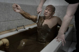 A worker removes oil from a guest at the Kepez resort in Naftalan, Azerbaijan, on Nov. 15, 2024. (Emile Ducke/The New York Times)