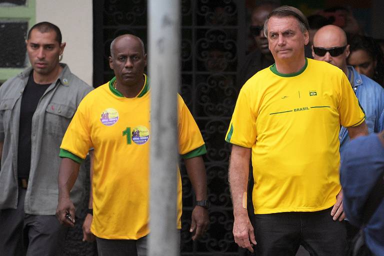 (FILES) Brazilian President and re-election candidate Jair Bolsonaro (C) leaves, accompanied by Ailton Gonçalves Moraes Barros (CENTRO) , a retired major of the Army, after voting during the legislative and presidential elections in Rio de Janeiro, Brazil, on October 2, 2022. - Police in Brazil searched ex-president Jair Bolsonaro's home on May 3, 2023, as part of an investigation into allegations of falsifying COVID-19 vaccination certificates. The far-right ex-president (2019-2022), who faced widespread criticism for his unorthodox handling of the pandemic, has repeatedly said he is not vaccinated against COVID-19. Ailton Gonçalves Moraes Barros, 61, former candidate for state deputy for the PL in Rio de Janeiro in 2022 and former army major, was arrested by the Federal Police. (Photo by CARL DE SOUZA / AFP)