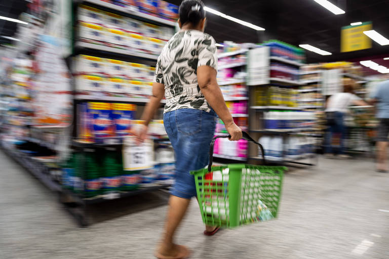 Imagem mostra consumidora com cesta de produtos em supermercado na zona leste de São Paulo