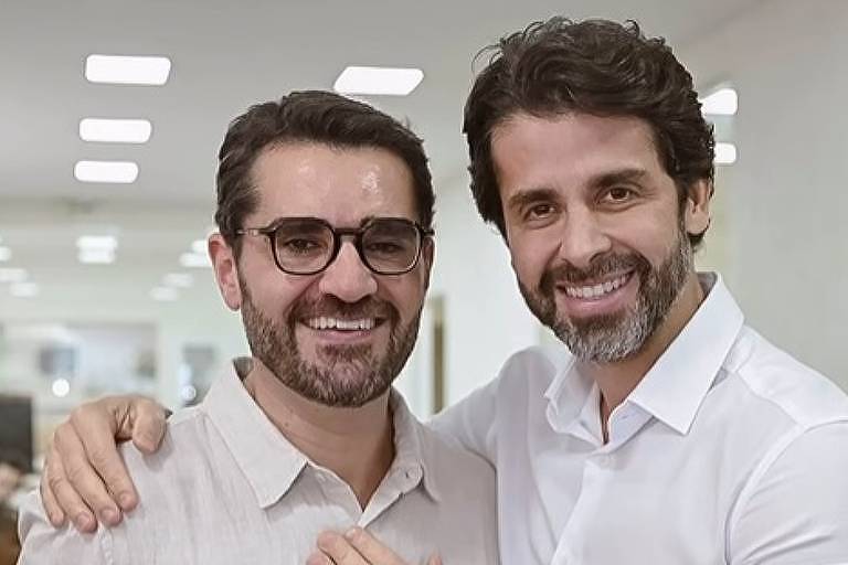 Em foto colorida, dois homens celebram o casamento