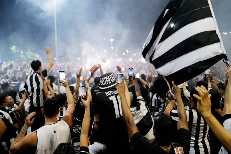 Torcedores cercam ônibus da equipe do Botafogo na chegada ao Rio de Janeiro um dia após a conquista da Libertadores; multidão recebe jogadores para comemorar o título neste domingo (1º) na praia de Botafogo.