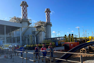 Workers walk outside Eneva power generation company's importing gas terminal in Aracaju