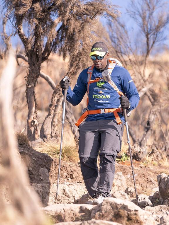 Homem negro caminha em direção ao topo do Kilimanjaro， na Tanzânia