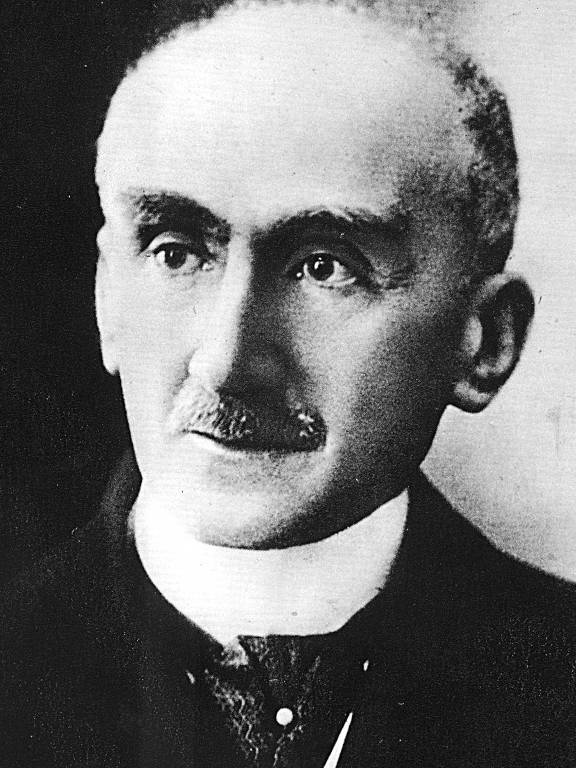 O filósofo francês Henri Bergson (1859-1941), autor de "Matérias e Memórias". A imagem é um retrato em preto e branco de um homem com cabelo curto e grisalho, usando um paletó escuro e uma gravata. Ele tem um bigode e uma expressão séria, olhando diretamente para a câmera.
