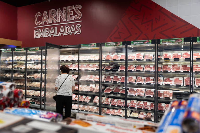 Imagem mostra pessoa escolhendo carnes em freezer de supermercado em São Paulo