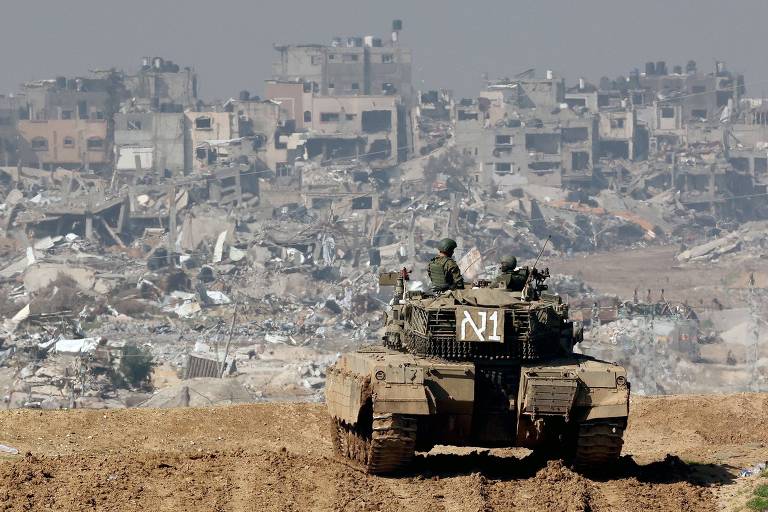 Tanque marrom em estrada de terra， posicionado à frente de prédios aruinados