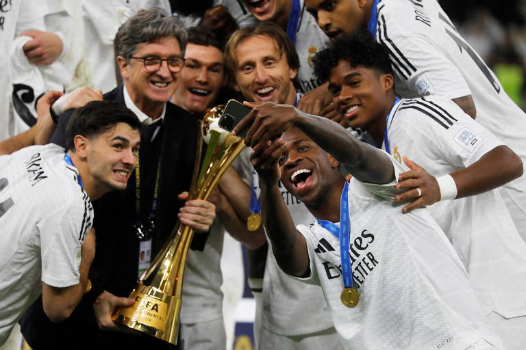 O jogador Vinicius Junior do Real Madrid, tira selfie com a taça e os companheiros de equipe durante comemoração do título na final da Copa Intercontinental no Qatar.