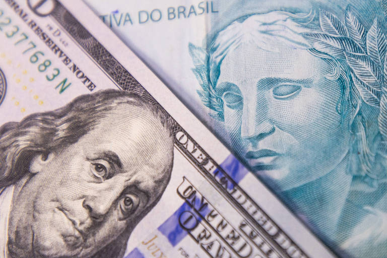 A imagem mostra uma nota de 100 dólares dos Estados Unidos em primeiro plano， com o retrato de Benjamin Franklin， e uma nota de 100 reais do Brasil ao fundo， destacando a figura de uma mulher com uma coroa de folhas. As notas estão sobrepostas parcialmente.