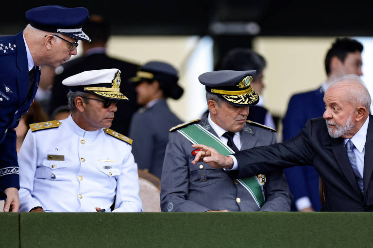 Homem de terno gesticula a militares com uniformes cinza, branco e azul