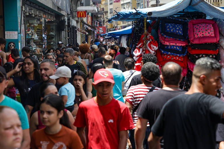 Multidão de pessoas caminha entre lojas e barracas.