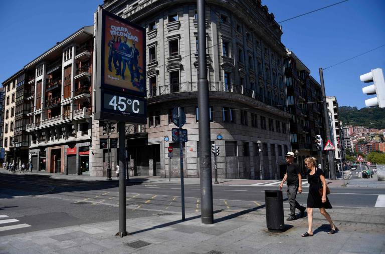 Um casal passa por um termômetro de rua que marca 45°C na cidade de Bilbao, na Espanha, durante a quarta onda de calor do verão no país europeu