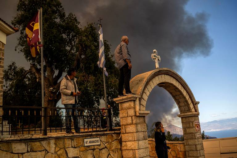 Moradores observam incêndio florestal na aldeia de Pyrgos, perto de Corinto, na Grécia; país foi um dos mais atingidos pelo fogo na Europa neste ano