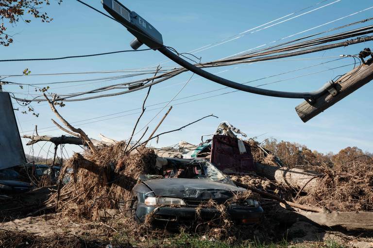 Destroços e carros destruídos permanecem ao longo da estrada um mês após o furacão Helene atingir a área em Asheville, Carolina do Norte (EUA)