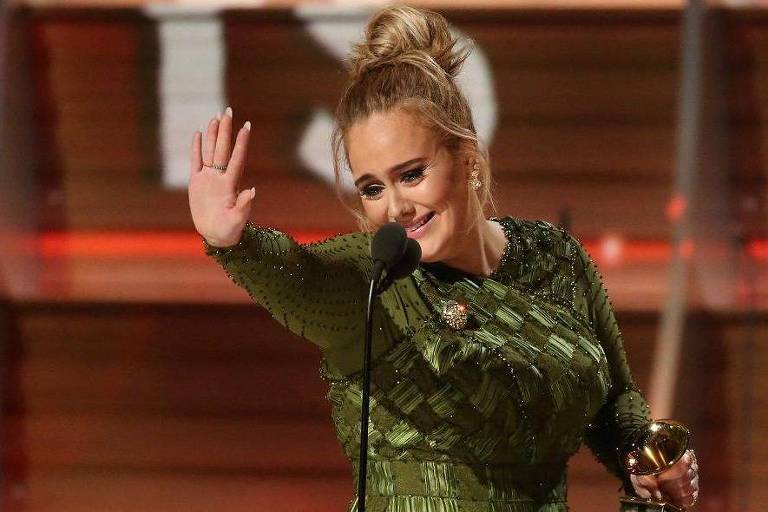 Adele acena com a estatueta do Grammy em uma das mãos