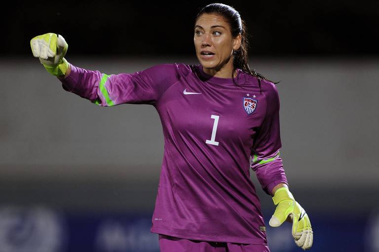 Usando uniforme púrpura com o número 1 estampado na camisa e luvas nas cores amarelo e branco， Hope Solo defende a seleção dos EUA em jogo pela Copa Algarve contra a Noruega， em Portugal