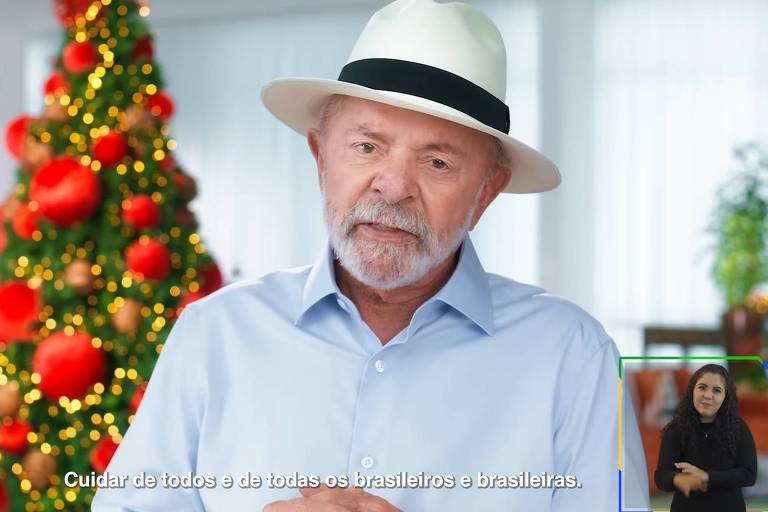 Lula fala em frente a uma arvore de natal. ele veste chapéu e camisa