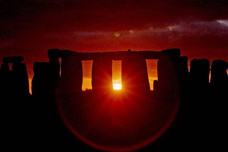 Foto mostra silhueta de Stonehenge ao pôr-do-sol