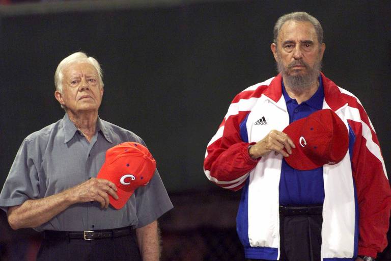 O ex-presidente dos Estados Unidos Jimmy Carter (esq.) e o ditador cubano Fidel Castro ouvem o hino nacional cubano no estádio de beisebol Latinoamericano, em Havana, Cuba