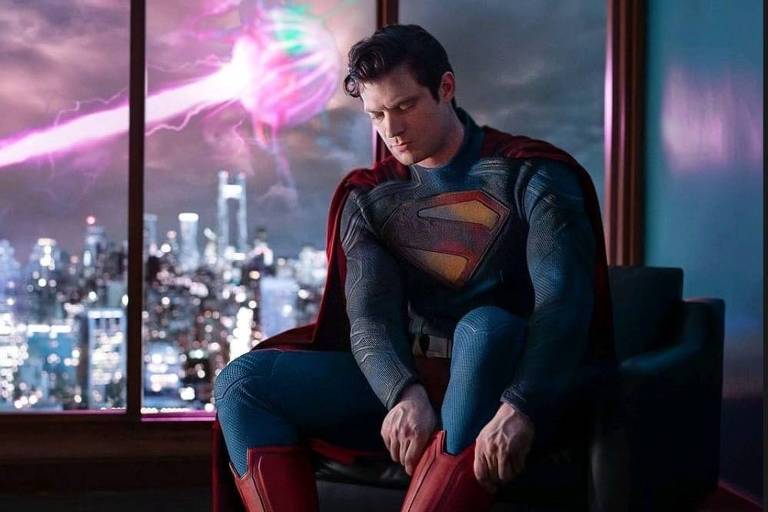 David Corenswet em cena promocional colocando o traje de 'Superman'; filme estreia em 2025