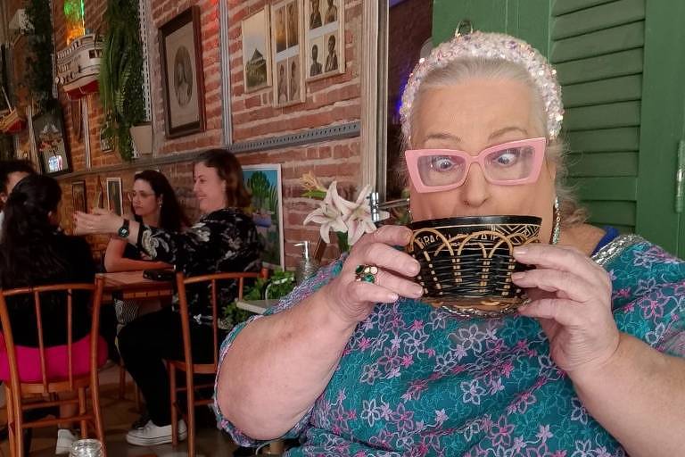 Em foto colorida, mulher aparece tomando chá e brinca com fotógrafo