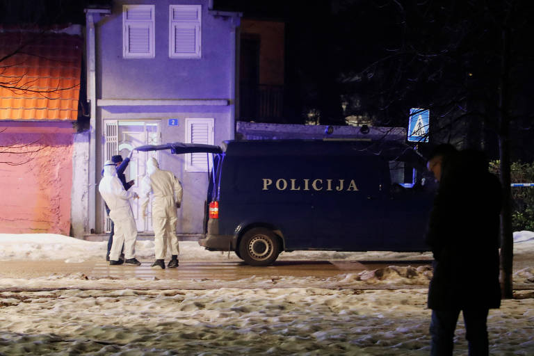 A imagem mostra uma cena de investigação policial à noite. Um veículo da polícia， identificado pela palavra 039;POLICIA039;， está estacionado em frente a uma casa. Dois indivíduos vestidos com trajes brancos de proteção estão próximos ao veículo， enquanto uma terceira pessoa， vestindo roupas escuras， observa a cena ao fundo. O ambiente é iluminado por luzes artificiais， criando um contraste com a neve no chão.