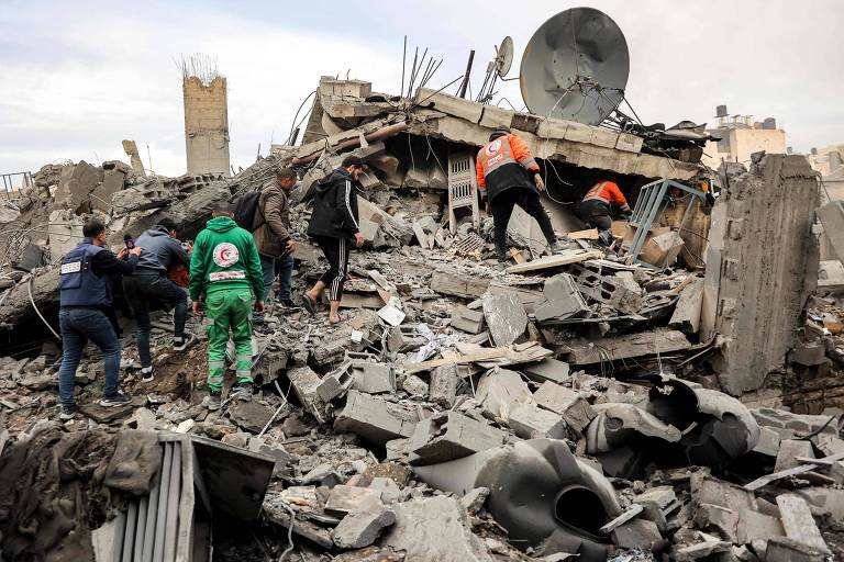 Moradores e socorristas procuram pessoas presas em escombros de edifício atingido por ataque de Israel em Gaza