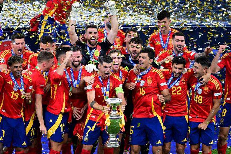 Jogadores da seleção da Espanha， reunidos， celebram em Berlim a conquista da Eurocopa de 2024， após derrotar a Inglaterra; o capitão do time， Morata， segura a taça