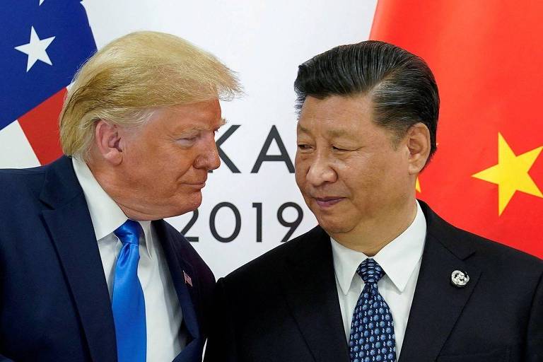 Fotografia colorida mostra Trump， um idoso branco de terno， e Xi Jinping um idoso amarelo de terno， conversando próximos
