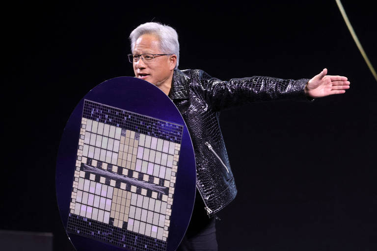 Imagem mostra Jensen Huang， um homem de cabelo grisalho， vestindo uma jaqueta preta brilhante， que está em um palco segurando um grande escudo com um design geométrico. Ele está gesticulando com a mão direita， enquanto a mão esquerda segura o escudo. O fundo é escuro， destacando a figura do apresentador e o escudo.