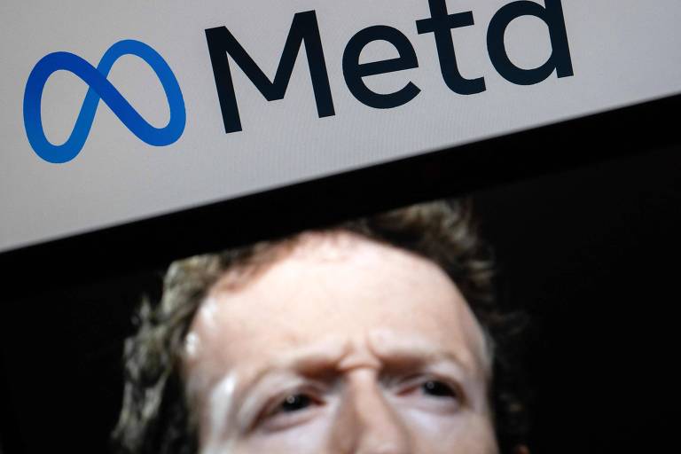 A imagem mostra o logotipo da Meta, que consiste em um símbolo azul em forma de infinito, acompanhado da palavra 'Meta' em letras pretas. A parte inferior da imagem apresenta um close do rosto de Zuckerberg. 