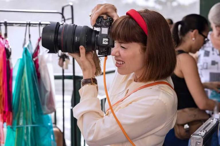 Em foto colorida, mulher aparece tirando fotos em um ponto turístico