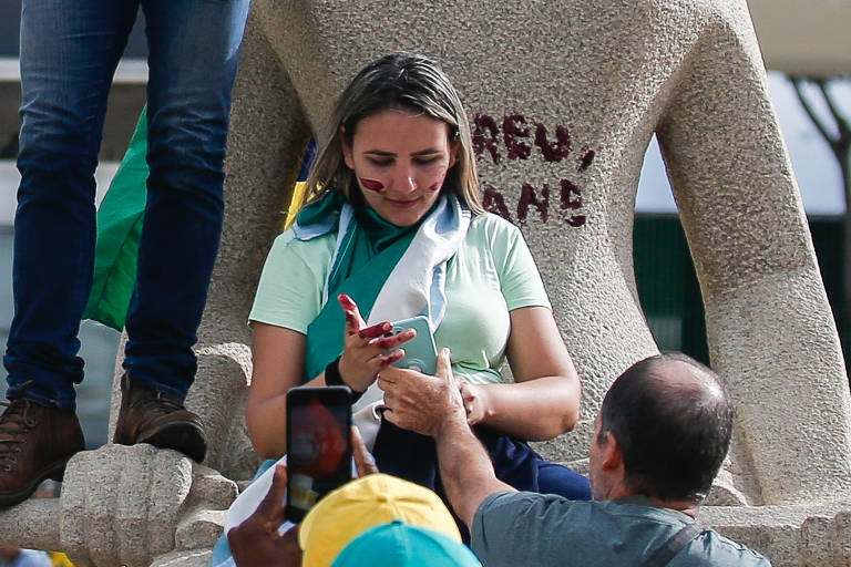 A grande maioria dos manifestantes chegou à capital federal de ônibus; na foto, a manifestante identificada como Débora Santos picha a estátua da Justiça, na praça dos Três Poderes