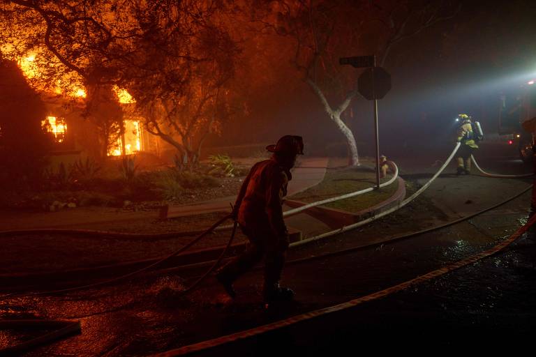 Imagem mostra bombeiro carregando mangueira durante trabalho de contenção das chamas