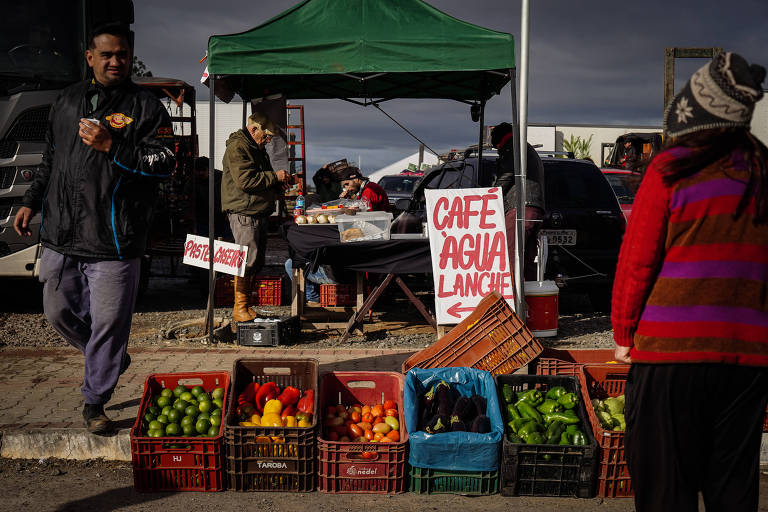 Foto mostra caixas de hortifrúti em central de abastecimento em Gravataí， na Grande Porto Alegre， durante período de enchentes no RS; pessoas circulam no local