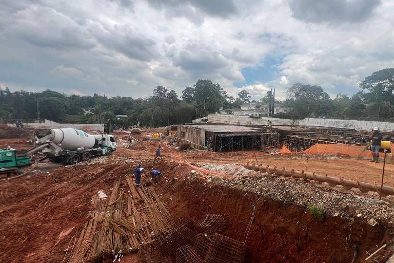 Fotografia de obras de um condomínio， com bastante terra e uma betoneira