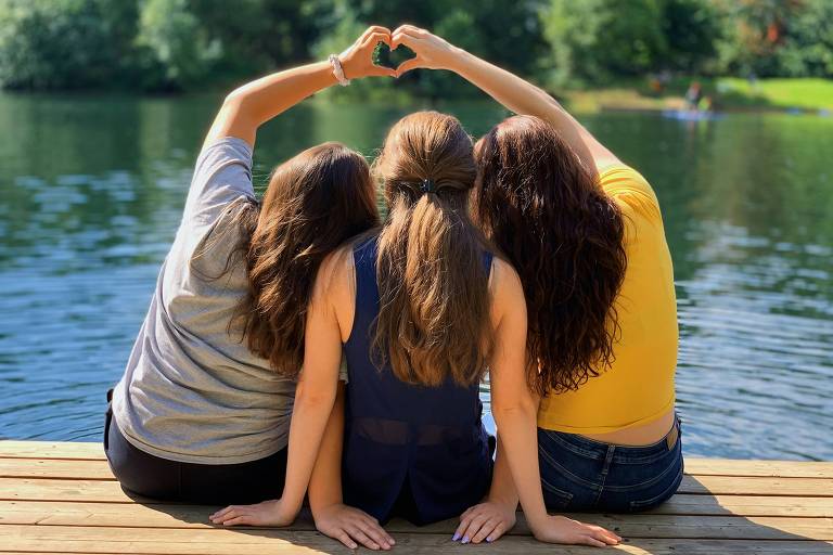 Três meninas sentadas em um lago