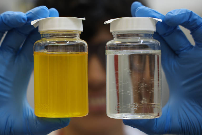 A bióloga Alessandra Ramin, 35, demonstra duas amostras de água (uma amarela, com contaminação para controle de padrão, e outra transparente, sem contaminação) em unidade de controle de qualidade da Sabesp, na estação de pré-condicionamento de esgoto em Santos, na Baixada Santista