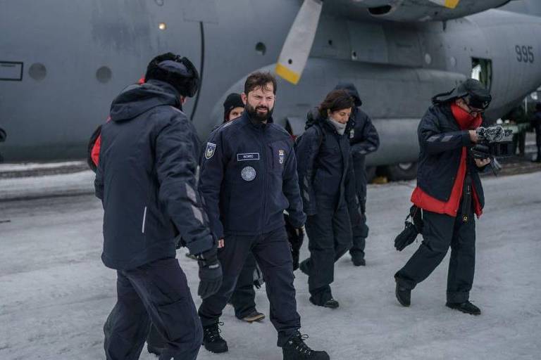 Foto mostra um grupo de homens brancos com trajes de neve desembarcando de um veículo sobre a neve. 