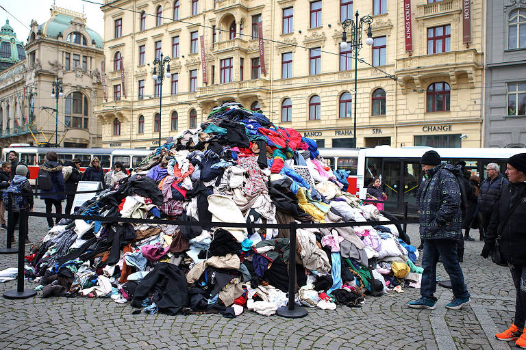 Instalação de pilhas de roupas usadas no centro de Praga, na República Tcheca, alerta para o problema global dos resíduos têxteis na era das fast fashions