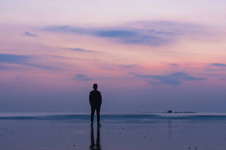 Imagem com cores violetas e rosas e um homem parado no centro